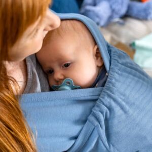 Close Caboo Lite Baby Carrier Denim - baby being carried on the front indoors by a mum with red hair.