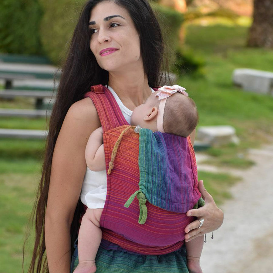 A woman standing in a park carrying her baby on her front with in a Girasol Mysol Paradise