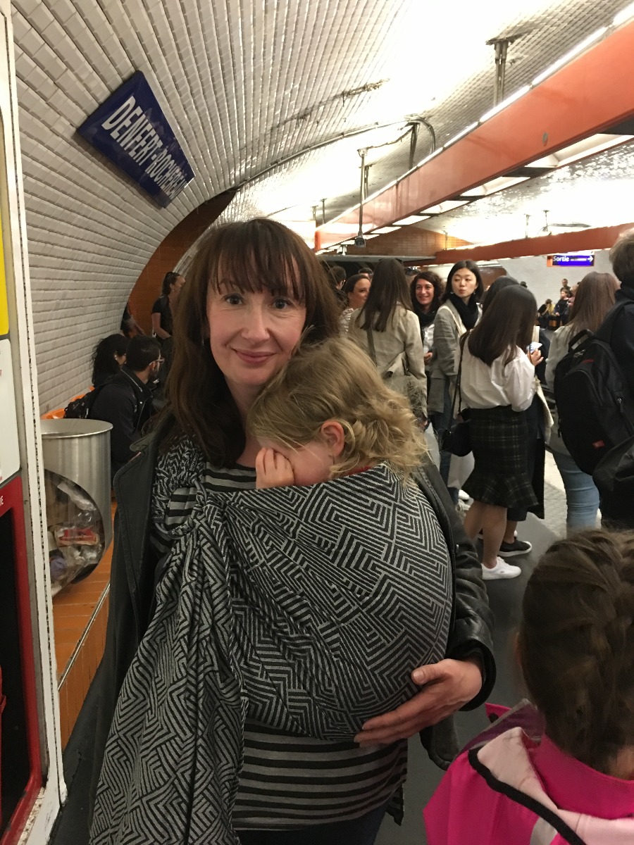 Beth carrying her toddler in a Didymos ring sling on the platform in the Paris Metro