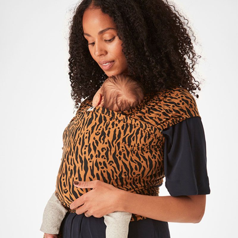 A woman carrying her newborn baby in the Coracor Zebra Terracotta Baby Wrap, resting her chin on the top of baby's head.
