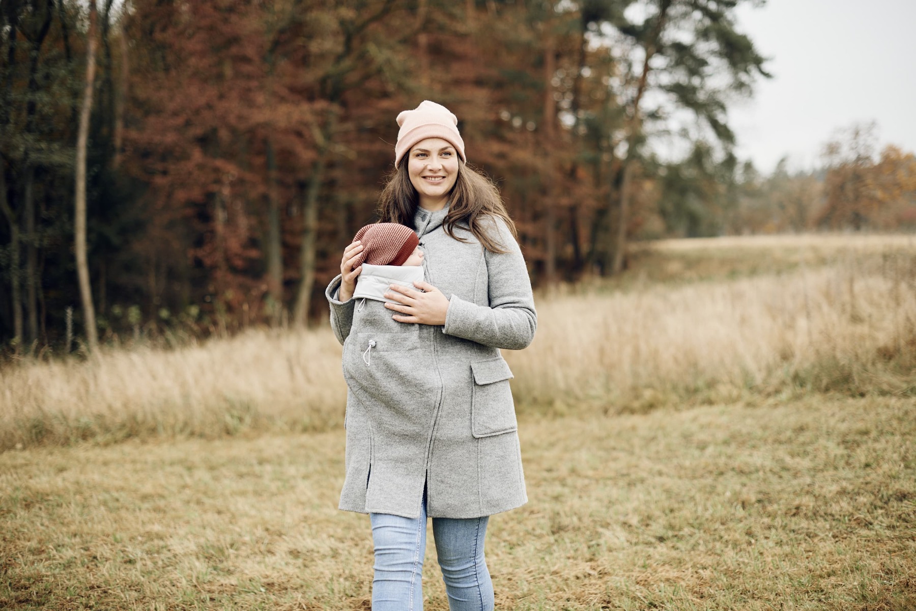 A woman wearing the Mamalila Wool Hooded Coat Vienna Grey outdoors in a field