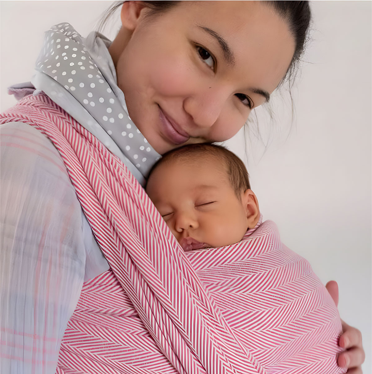 A close up of a baby sleeping in a Didymos Lisca Raspberry woven wrap. The picture highlights the herringbone weave of the fabric.
